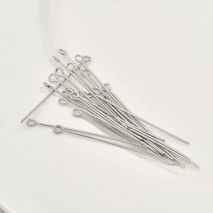 Top-down shot of silver-colored metal eye pins for DIY jewelry making on white ceramic