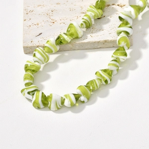 Green and white marble textured heart-shaped glass bead necklace on a beige stone stand