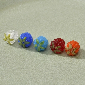 Detail of colorful handmade glass berry beads with green leaves for DIY jewelry making