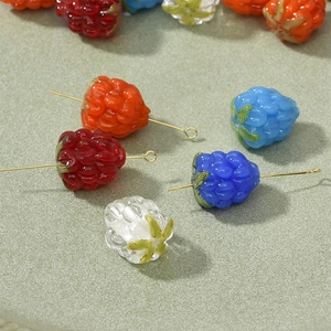 Macro shot of glass berry beads with green leaves and metal pins for DIY jewelry making