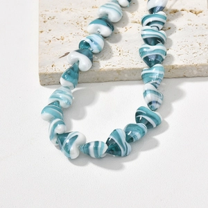Macro shot of heart-shaped glass beads with blue and white marble texture on stone