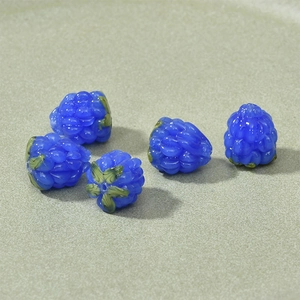Macro view of blue berry glass beads with green leaves for DIY jewelry making
