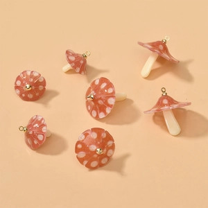 Flat lay of seven red mushroom acrylic pendants with white dots and gold hooks