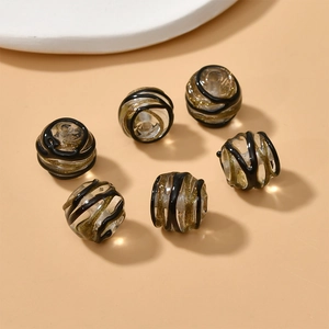 Macro detail of 13mm handmade glass beads with gold glitter and black spiral patterns