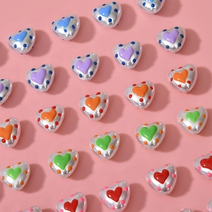 Close-up of colorful heart-shaped metallic beads with polka dots for DIY jewelry making