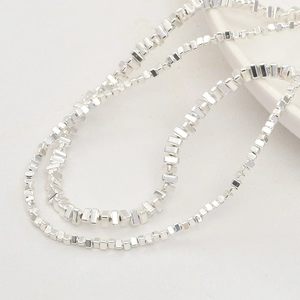 Close-up of irregular silver metallic beads on a textured surface for jewelry making