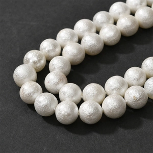 Macro view of creamy white cotton pearl beads with unique textured wrinkled surface