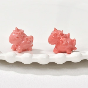 Macro detail of pink resin unicorn charms with wings on a white ceramic plate