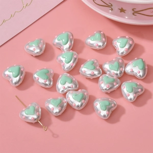 Detail of pearlescent heart beads with pink dots and vertical hole for DIY jewelry