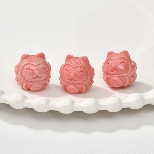 Close-up of pink cat-shaped lucky beads with 'Fu' engraving for jewelry making