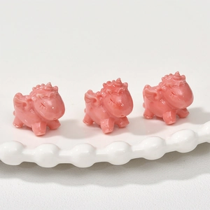 Macro detail of pink resin unicorn charms with cute wings and sleeping expression on a tray
