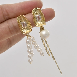 Dettaglio orecchino placcato oro 14k con consistenza lavica, zircone e nappe di perle