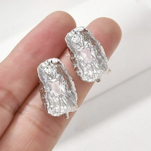 Dettaglio macro dell'orecchino a lobo in zircone con trama in metallo stropicciato oro 14k