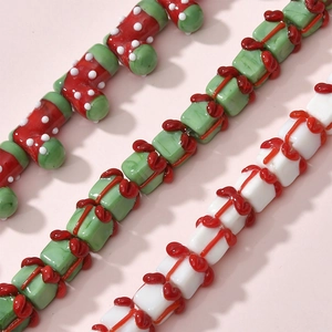 Detailed view of Christmas themed lampwork glass beads featuring stockings and gift boxes