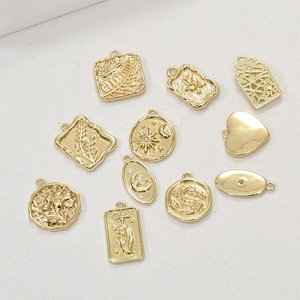 Detail of 14k gold-plated tarot style pendants featuring sun, moon, and floral engravings