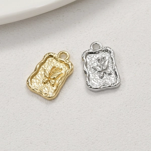 Macro detail of rectangular butterfly relief pendants with hammered texture and molten edges