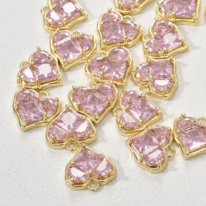 Dettaglio macro di ciondoli a cuore placcati oro 14k con zirconi rosa per gioielli DIY