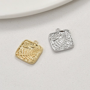 Detailed relief of leaf and feather patterns on square gold and silver jewelry pendants