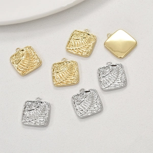 Close-up of square 14k gold and silver pendants with embossed fern leaf pattern