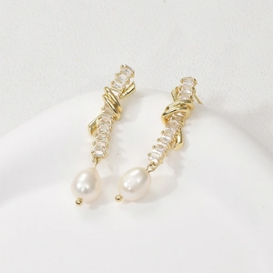 Detailed close-up of 14k gold plated earrings with zircon bars and white pearl drops