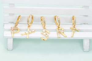 Detailansicht vergoldeter Buchstaben-Ohrringe mit glitzerndem Zirkonia-Inlay