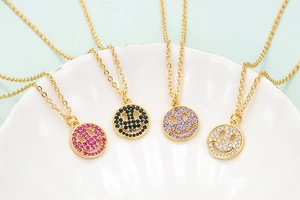 Detail of four gold box chains with zircon smiley face pendants in multiple colors