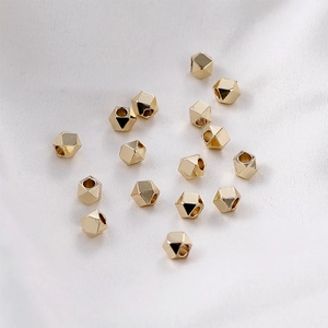 Vue macro détaillée de perles géométriques plaquées or 14k sur un fond en soie douce