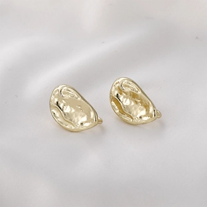 Close-up of golden baroque waterdrop earrings with a unique hammered metal texture