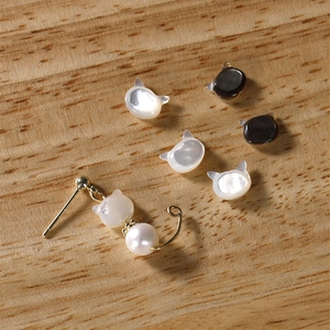 Detailed view of cat-shaped mother of pearl beads and a gold kitten earring with pearl