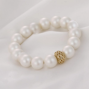 Dettaglio ravvicinato della perla traforata in oro 14k su un bracciale di perle bianche