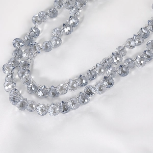 Macro shot of light blue faceted teardrop crystal beads on a silky white fabric