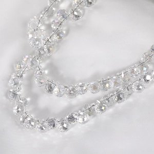 Macro shot of multifaceted crystal teardrop beads on white satin for jewelry making