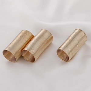 Close-up of three golden memory wire spring rings for jewelry making on white silk fabric