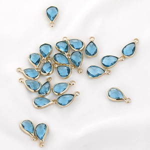 Macro detail of faceted teardrop crystal glass charms with golden metal edges