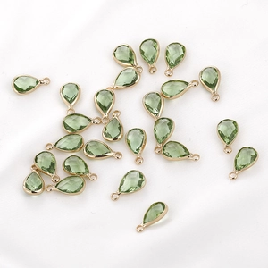 Macro detail of teardrop-shaped light green faceted crystal pendant with gold rim