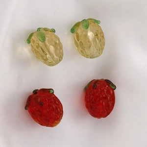 Detailed view of handmade glass fruit beads in pineapple and strawberry shapes for DIY jewelry