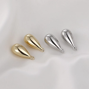 Polished 14k gold and silver teardrop pendants for DIY jewelry making on white silk