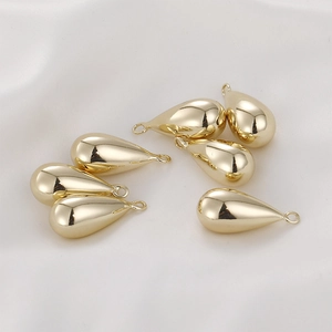 Close-up of 14k gold-filled teardrop charms on elegant white satin for DIY jewelry making