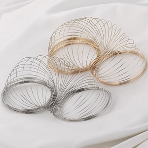 Bracciali a molla in filo armonico placcati oro 14k e argento su sfondo di seta bianca