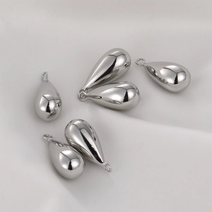 Macro view of six polished silver teardrop pendants on white fabric for DIY jewelry making