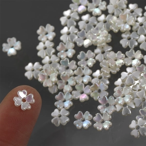 Macro detail of tiny iridescent shell-like five-petal flower beads for DIY jewelry making