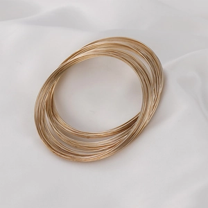 Dettaglio macro dei bracciali a molla placcati in oro 14k su seta bianca