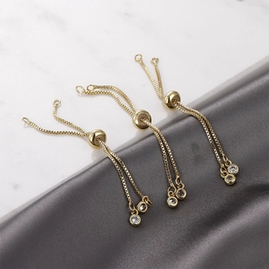 Dettaglio di catene box placcate oro 14k con perline scorrevoli e ciondoli zircone