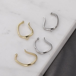 Close-up of gold and silver plated twist ear cuffs on a marble and fabric background
