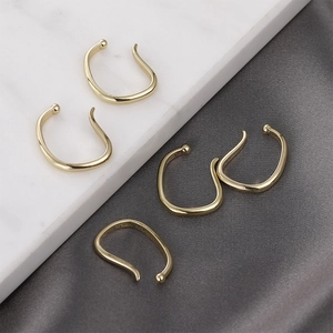 Five pieces of minimalist gold plated ear cuffs set on marble and velvet surface