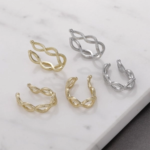 Detail of five gold and silver twisted cuff earrings on a white marble surface