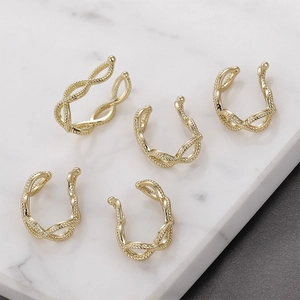 Detailed close-up of five gold twisted rope ear cuffs on a marble surface