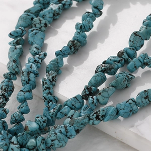 Macro shot of irregular turquoise stone beads with natural black veins on white marble