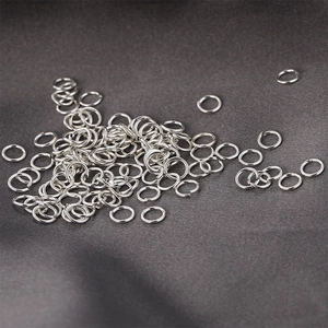 Macro shot of silver open jump rings for DIY jewelry making on dark silk fabric