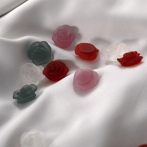 Close-up of matte resin rose flower charms in pink and white on silk fabric